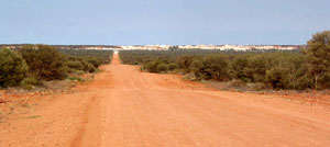 Vom Stuart Highway zweigt bei Marla die unbefestigte Piste nach Mintabie ab. Nach etwa 35 Kilometern durch ebenes Buschland ist der Opalort erreicht